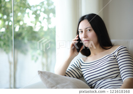 Serious asian woman talking on phone looking at you Serious asian woman talking on phone looking at you 121618168