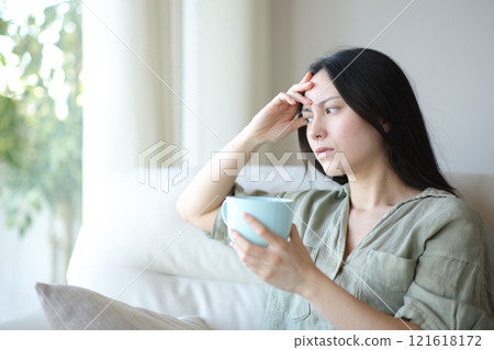 Worried asian woman drinking coffee at home Worried asian woman drinking coffee at home 121618172