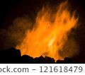 Intense orange flames and smoke rise against a dark background, depicting the burning of fossil fuels like coal or oil. Close-up detail highlights the heat, energy, and pollution generated by this co 121618479