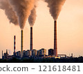 Industrial power plant emitting smoke and steam against a soft, peach-colored sunset sky. Concept of air pollution, fossil fuels, climate change, and environmental impact. 121618481
