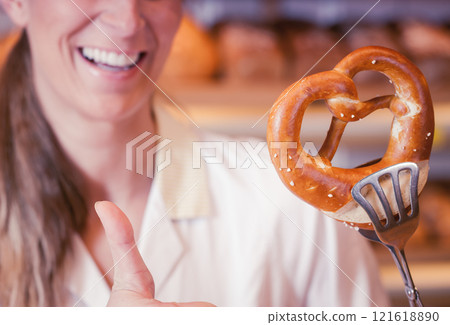 Bakery sales lady presenting a pretzel Bakery sales lady presenting a pretzel 121618890