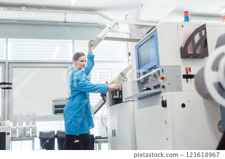 Woman worker at visual inspection of PCB on electronics assembly line 121618967