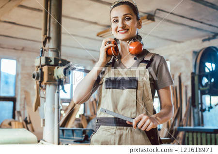 Beautiful woman carpenter in her woodwork workshop Beautiful woman carpenter in her woodwork workshop 121618971