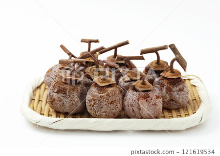 Dried persimmons with stems on a sieve on a white background Dried persimmons with stems on a sieve on a white background 121619534