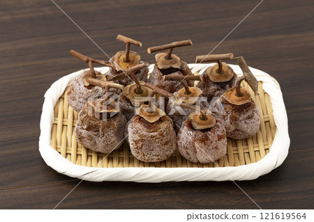 Dried persimmons with stems on a colander against a wooden background 121619564