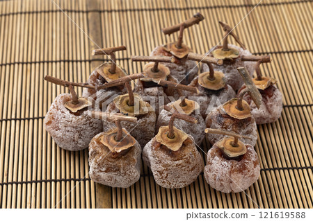Dried persimmons with stems on bamboo mat background 121619588