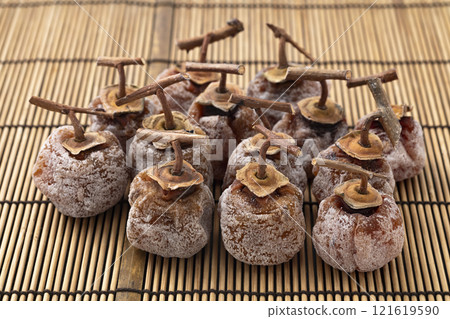 Dried persimmons with stems on bamboo mat background 121619590