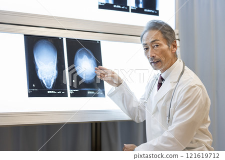 A veteran doctor explaining something while looking at an X-ray of the head 121619712