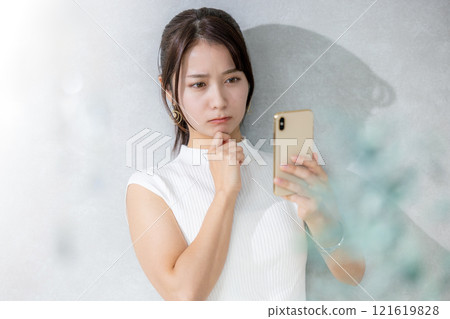 年輕女子在客廳看智慧型手機 121619828