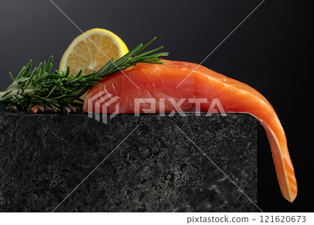 Smocked salmon with rosemary, lemon, and peppercorn on a black background. 121620673