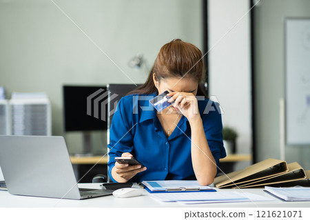 Serious woman cover her face after stressed with credit card debt sit at workplace desk in office use calculator calculates monthly expenses. 121621071