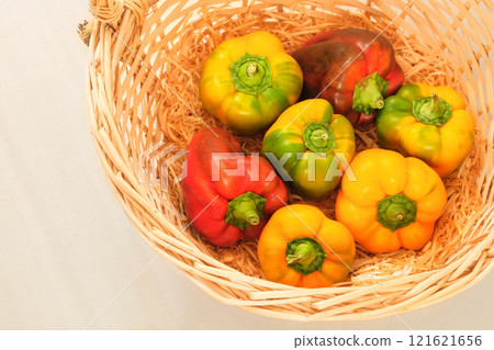 Sweet peppers in a straw basket. Orange and red ripe vegetables. Top view 121621656