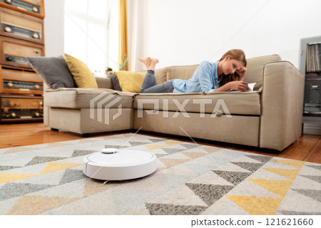 Modern robot vacuum cleaner, woman relaxing Modern robot vacuum cleaner, woman relaxing 121621660