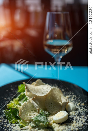 caesar salad with chicken, lettuce and croutons on black plate in restaurant caesar salad with chicken, lettuce and croutons on black plate in restaurant 121622204