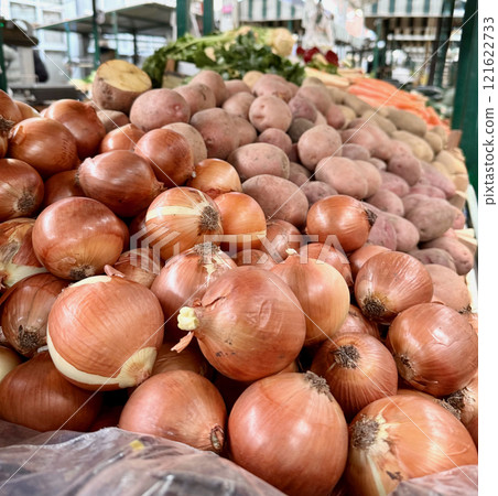 A fresh organic market stall filled with fresh vegetables, including onions, potatoes, and carrots 121622733