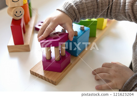 Child playing a fun-filled game of logic with colourful wooden blocks. Child playing a fun-filled game of logic with colourful wooden blocks. 121623204