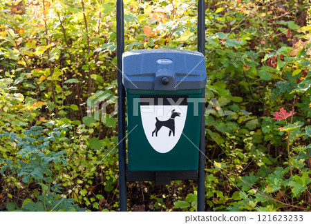 Green dog waste bin container in a park. Dog excrement cleaning, 121623233