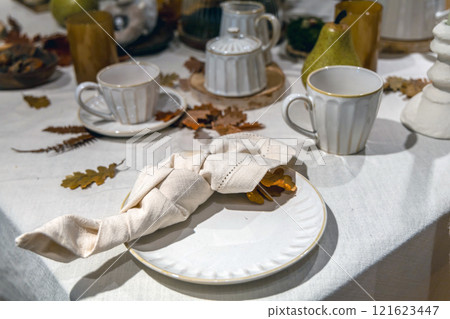 A Thanksgiving dinner table set with plates, cups, and napkins A Thanksgiving dinner table set with plates, cups, and napkins 121623447