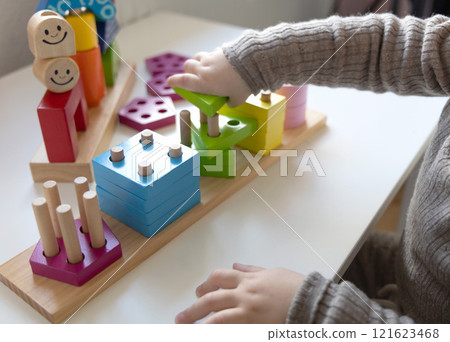 Child playing a fun-filled game of logic with colourful wooden blocks. 121623468