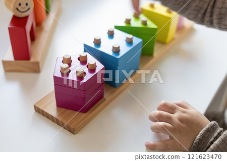 Child playing a fun-filled game of logic with colourful wooden blocks. Child playing a fun-filled game of logic with colourful wooden blocks. 121623470