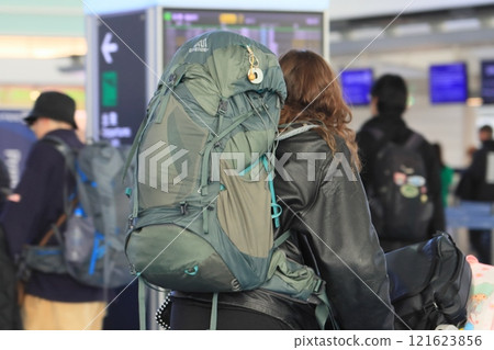 Traveler carrying a large backpack, airport lobby view Traveler carrying a large backpack, airport lobby view 121623856
