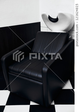 Stylish black salon chair positioned next to a unique hair washing station Stylish black salon chair positioned next to a unique hair washing station 121624815