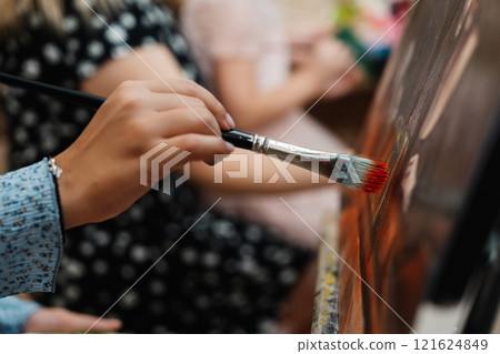 A person painting on canvas during an art class in a bright studio A person painting on canvas during an art class in a bright studio 121624849