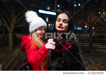 Woman and girl enjoying a nighttime stroll in a city park during winter 121624929