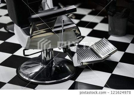 Modern barber chair with footrest in a stylish black and white salon Modern barber chair with footrest in a stylish black and white salon 121624978