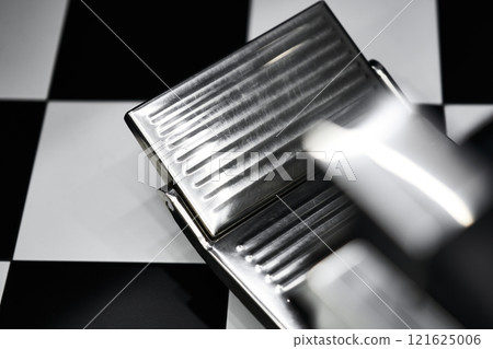 Close-up view of a chrome foot pedal on a checkerboard surface in a workshop 121625006