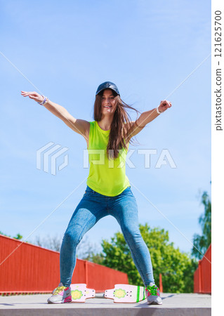 Teen girl skater riding skateboard on street. Teen girl skater riding skateboard on street. 121625700