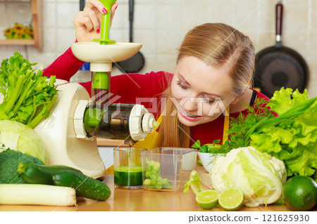 Woman in kitchen making vegetable smoothie juice Woman in kitchen making vegetable smoothie juice 121625930