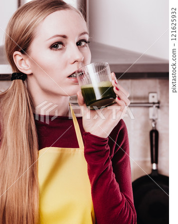 Woman in kitchen holding vegetable juice Woman in kitchen holding vegetable juice 121625932