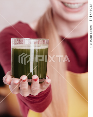 Woman in kitchen holding vegetable juice 121625938