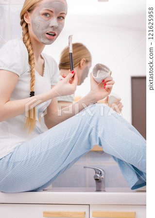 Woman applying with brush clay mud mask to her face Woman applying with brush clay mud mask to her face 121625958