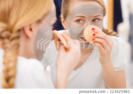 Woman removing mud facial mask with sponge Woman removing mud facial mask with sponge 121625962