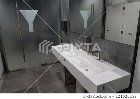 A spacious bathroom showcases a sleek, modern sink with dual faucets and a minimalist aesthetic. Frosted glass partitions add privacy, creating a contemporary atmosphere for users A spacious bathroom showcases a sleek, modern sink with dual faucets and a minimalist aesthetic. Frosted glass partitions add privacy, creating a contemporary atmosphere for users 121626152