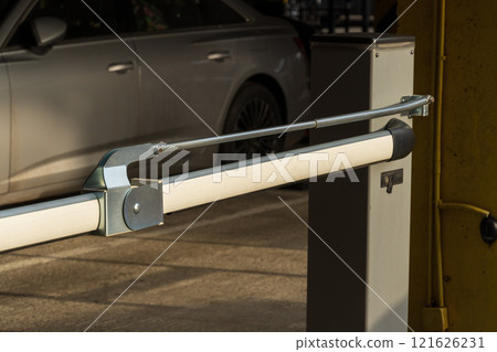 An automatic barrier stands closed at the entrance of the parking lot, preventing unauthorized entry and maintaining security for vehicles. The equipment is designed for efficient access control An automatic barrier stands closed at the entrance of the parking lot, preventing unauthorized entry and maintaining security for vehicles. The equipment is designed for efficient access control 121626231
