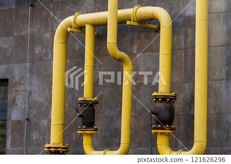 Yellow metal pipes are showcased in a industrial area, forming a complex system for transporting gas. The structure highlights various connections and valves for efficient energy management 121626296
