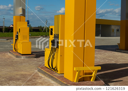 Bright yellow gasoline dispensers stand ready at a modern gas station. The setting is spacious with clear blue skies, showcasing an inviting atmosphere for vehicles needing fuel Bright yellow gasoline dispensers stand ready at a modern gas station. The setting is spacious with clear blue skies, showcasing an inviting atmosphere for vehicles needing fuel 121626319