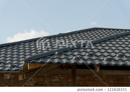 This residential rooftop showcases a sleek modern design with metallic tiles. The roofing process is underway, providing a durable and stylish covering for homes 121626331