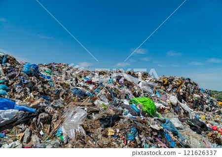 A vast landfill overflowing with trash and plastic debris contrasts starkly against a bright blue sky, highlighting the critical issue of waste management and pollution affecting ecosystems A vast landfill overflowing with trash and plastic debris contrasts starkly against a bright blue sky, highlighting the critical issue of waste management and pollution affecting ecosystems 121626337