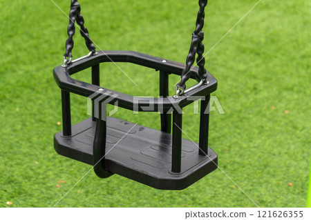 A sturdy swing designed for young children hangs in a vibrant green park. This play equipment offers endless fun and happiness for kids enjoying their outdoor adventures A sturdy swing designed for young children hangs in a vibrant green park. This play equipment offers endless fun and happiness for kids enjoying their outdoor adventures 121626355