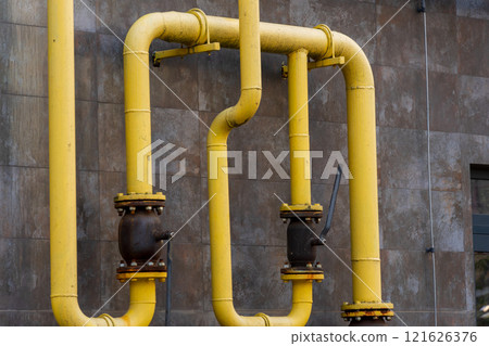Yellow gas pipes are installed on a building's exterior, connecting energy sources effectively. The arrangement illustrates technology and infrastructure for fuel distribution in urban environments 121626376