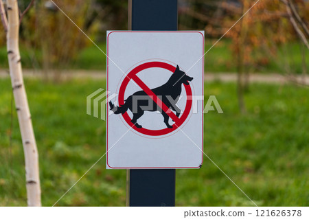 Brightly colored sign indicates that dog walking is not allowed in this park. The warning symbol features a silhouette of a dog with a prohibition mark Brightly colored sign indicates that dog walking is not allowed in this park. The warning symbol features a silhouette of a dog with a prohibition mark 121626378