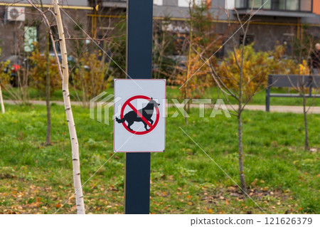 A warning sign is prominently placed in a grassy area, indicating that dog walking is prohibited. The symbol shows a dog inside a red circle with a slash, reinforcing the rule 121626379