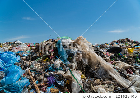 A vast amount of waste, including plastic and debris, tarnishes the landscape under a blue sky, underscoring the pressing need for better waste management and recycling 121626409