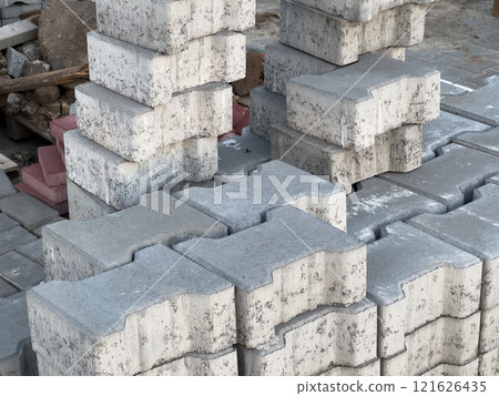 Stacked sections of grey paving stones and bricks ready for sidewalk and street construction, showcasing urban materials and an organized construction site setting 121626435