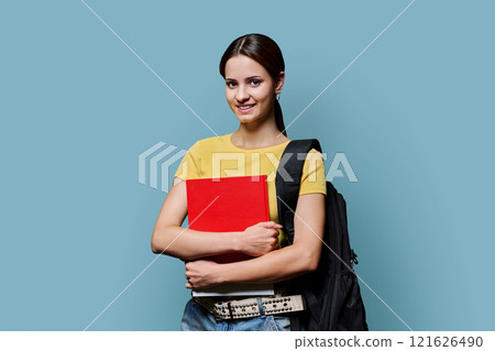 Portrait of teenager student girl holding notebook looking at camera on blue background Portrait of teenager student girl holding notebook looking at camera on blue background 121626490