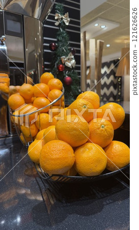 Basket of Fresh Oranges Displayed on a Countertop Near Festive Decorations Basket of Fresh Oranges Displayed on a Countertop Near Festive Decorations 121626626